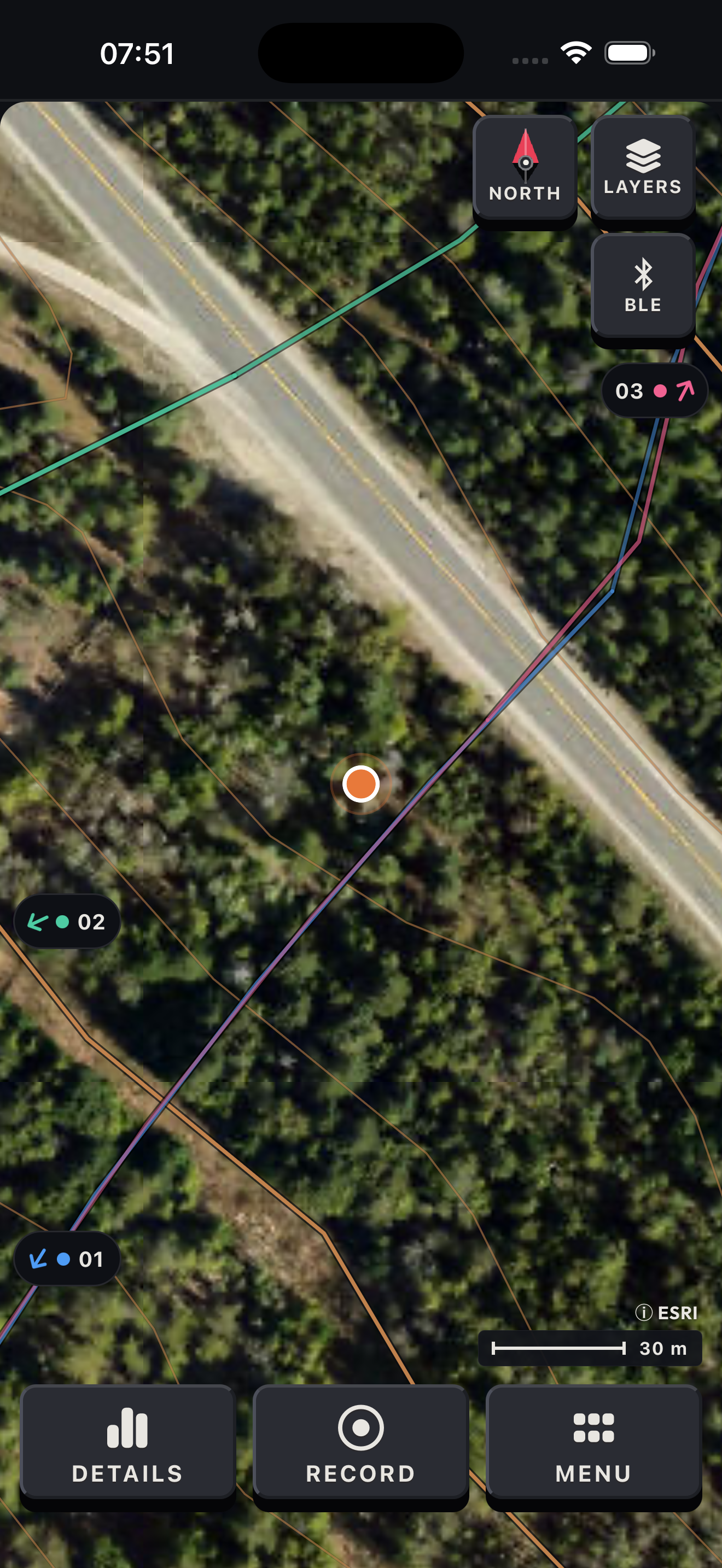 Earlier native iPhone simulator map with a simulated orange self-position, received coloured rider trails and example rider edge chips 01, 02 and 03. Satellite imagery and its Esri attribution are visible.